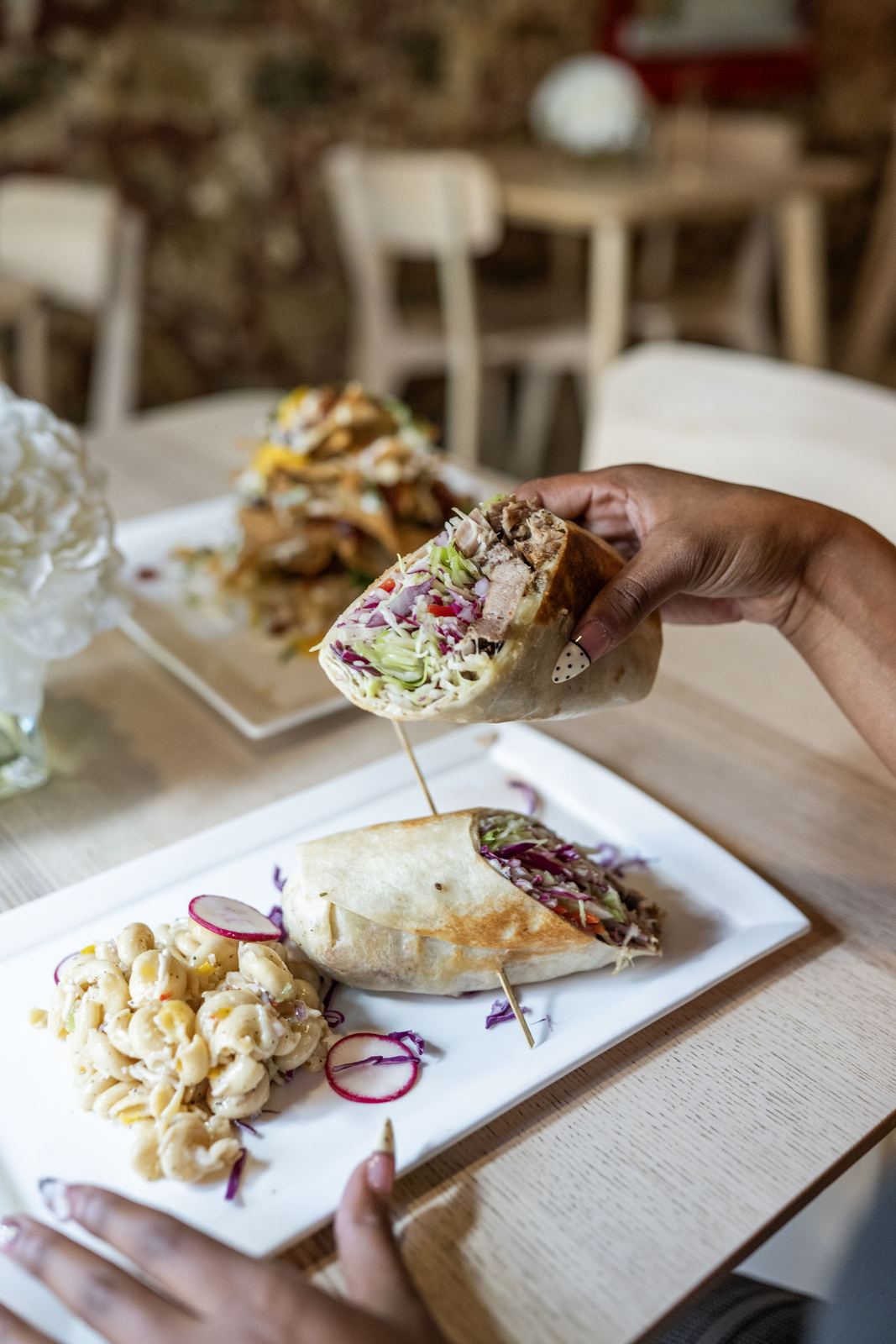 Lunch at Island Grind, a wrap lifted off the plate with mac salad on the side